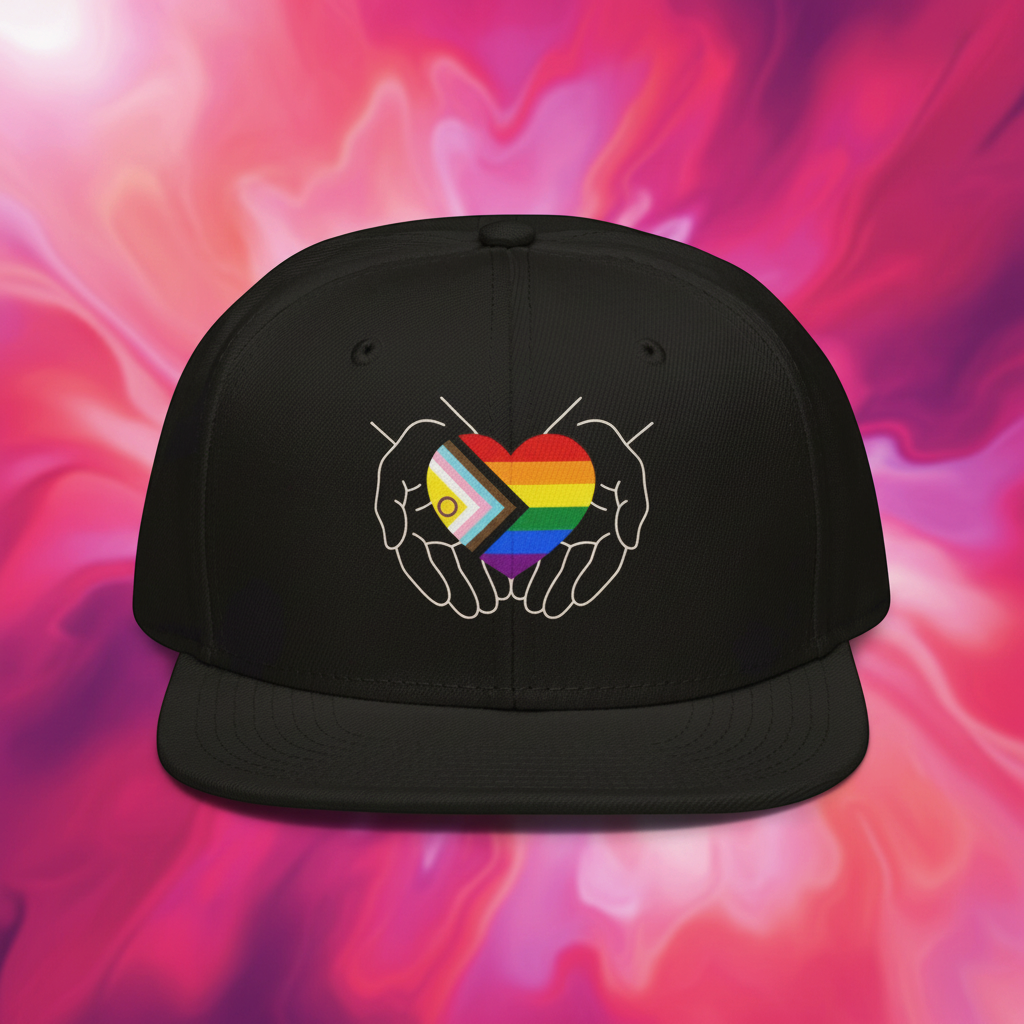 Flaunt It structured snapback cap featuring a Progress Pride heart in hands graphic worn by a smiling woman at a cafe