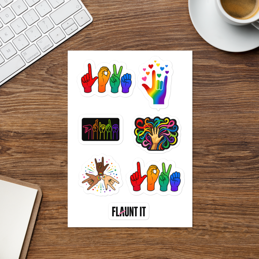 Flaunt It ASL Pride sticker sheet featuring colorful hand signs and rainbow designs on a wooden desk surface.