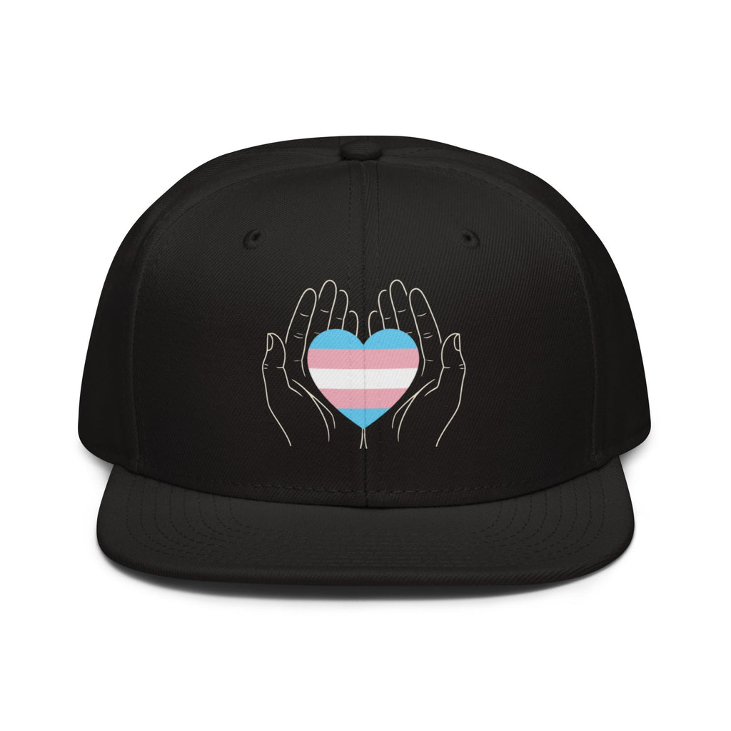 Flaunt It black snapback cap featuring a line-art graphic of hands holding a trans pride flag heart.