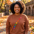 A smiling woman wearing a Flaunt It brown heavyweight cotton long sleeve shirt with a pride maple leaf branch design.