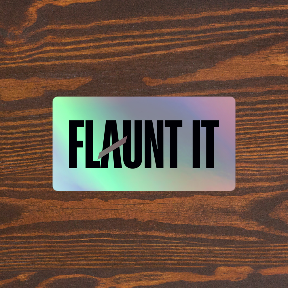 Flaunt It holographic vinyl sticker with black logo text on a dark wood grain background.