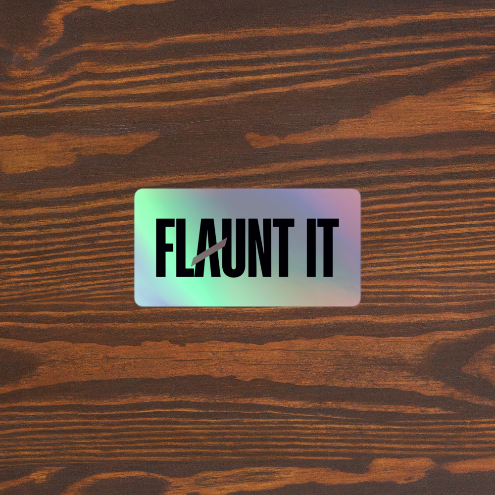 Flaunt It holographic vinyl logo sticker with a 3D embossed effect on a dark wood background.