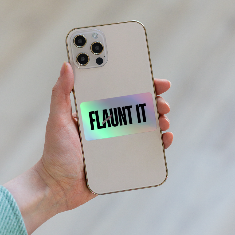 Flaunt It holographic vinyl logo sticker applied to the back of a smartphone held in a hand
