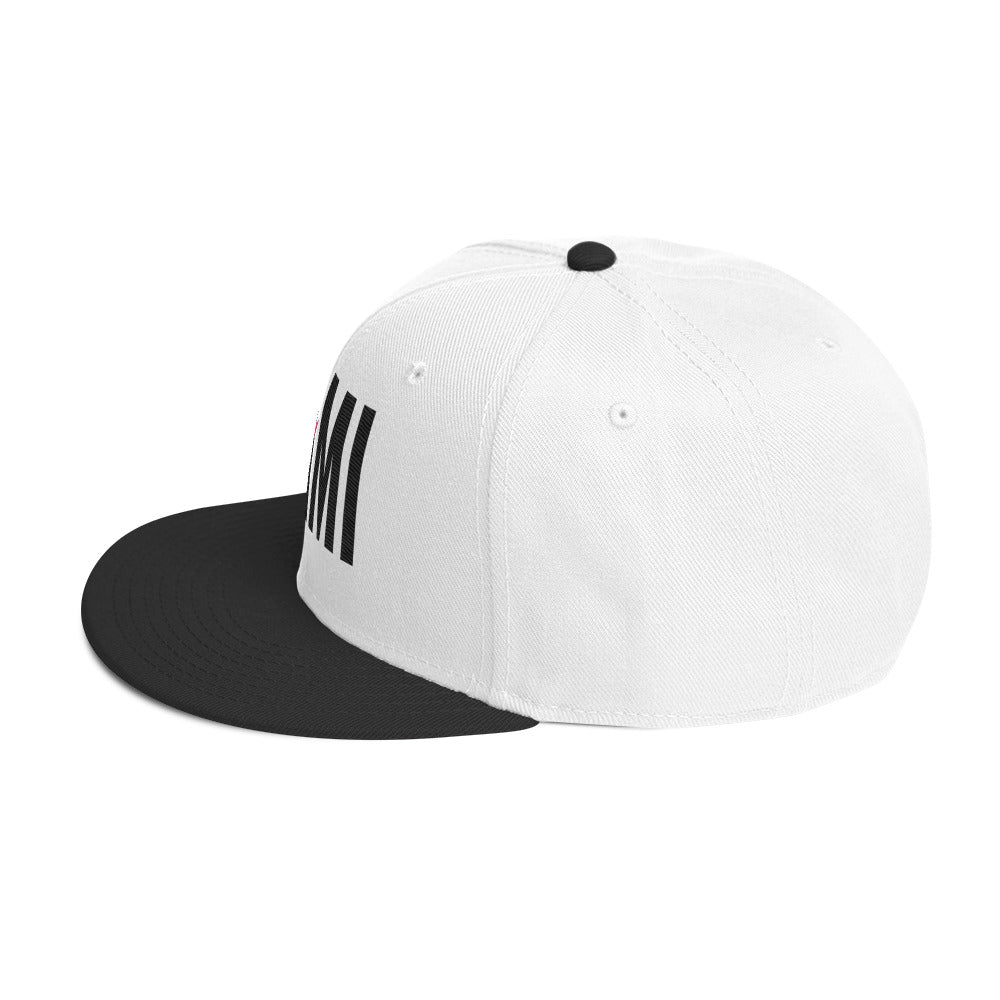 Flaunt It Mami embroidered snapback hat with a white crown, black flat brim, and black MAMI text embroidery.