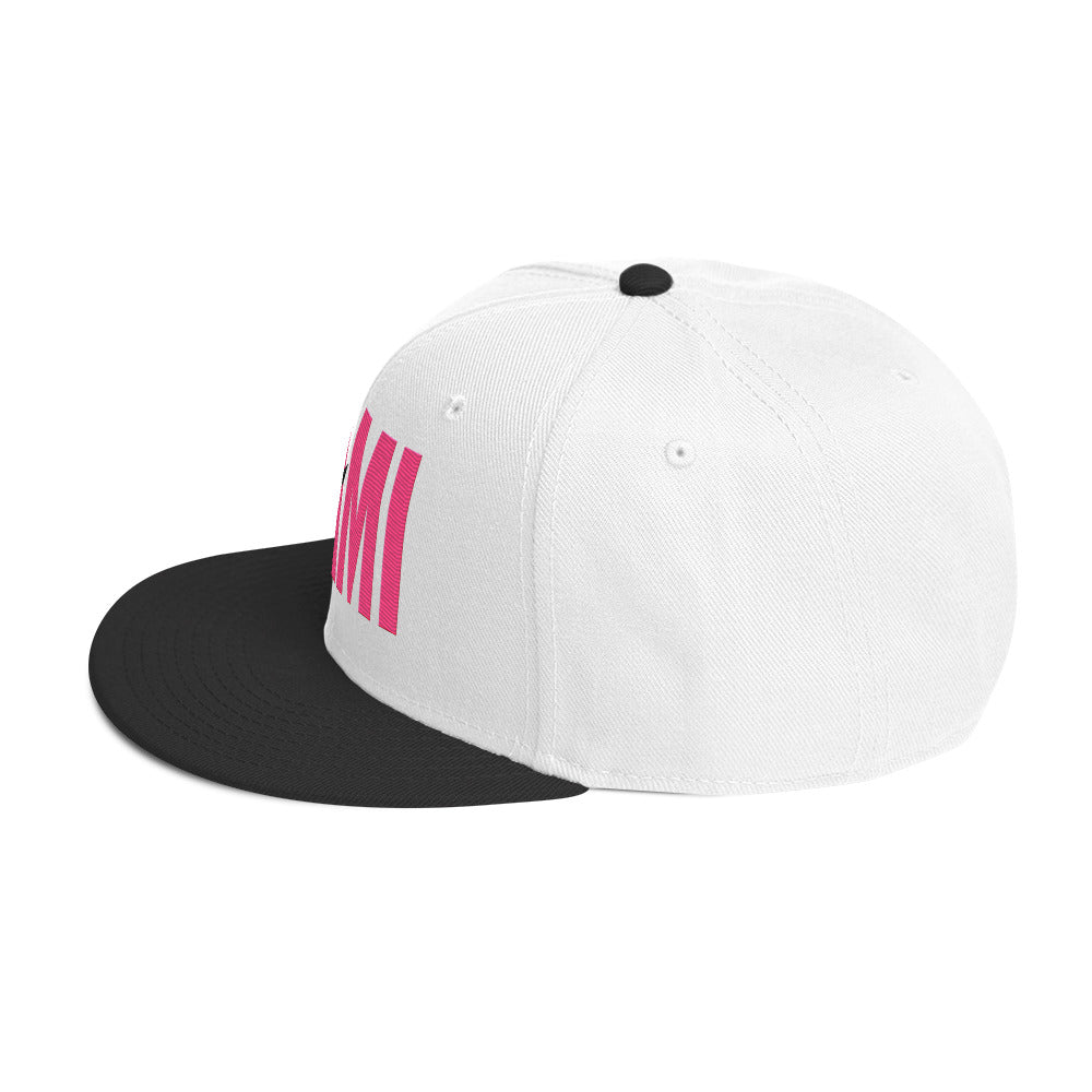 Flaunt It Mami embroidered snapback hat with white crown, black flat brim, and pink MAMI text with diagonal slash.