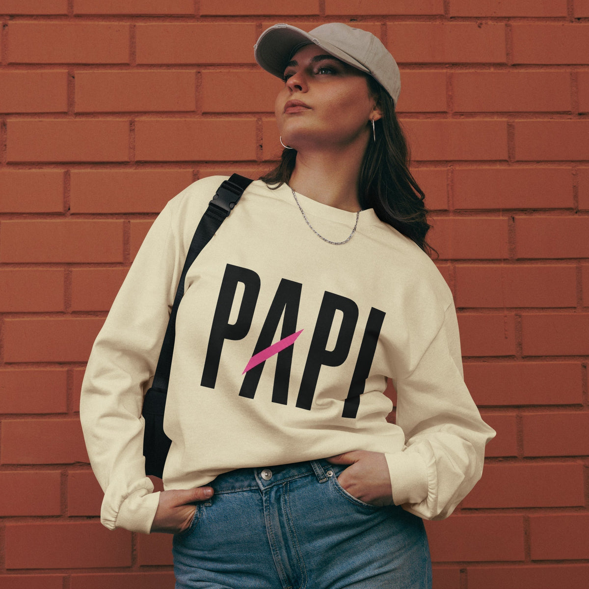 Flaunt It Papi heavyweight long sleeve shirt in cream with black text and pink slash, worn by a model in a cap.
