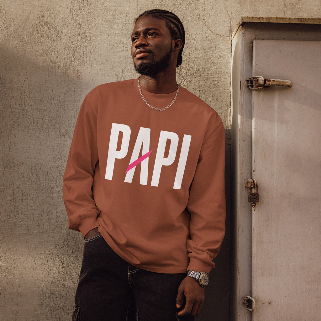 Flaunt It Papi heavyweight long sleeve shirt in rust with white text and a pink slash, worn by a man outdoors.