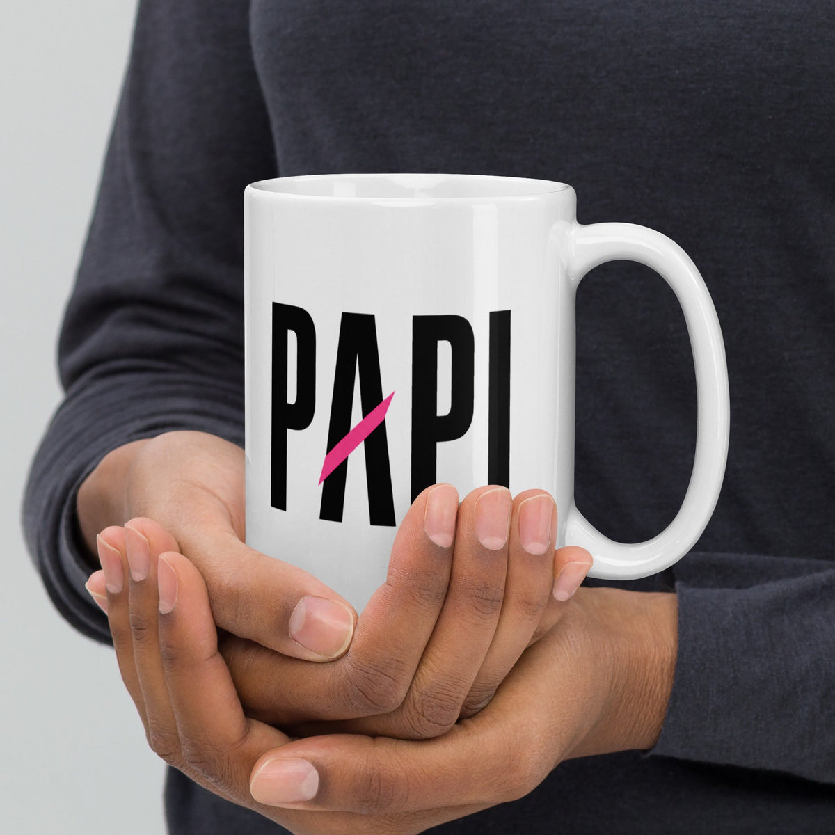 Flaunt It white ceramic mug held in hands, featuring black PAPI text with a vibrant pink slash through the letter A.
