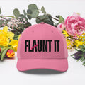 Flaunt It pink six-panel mesh-back cap with black embroidered wordmark logo, styled with colorful spring flowers.