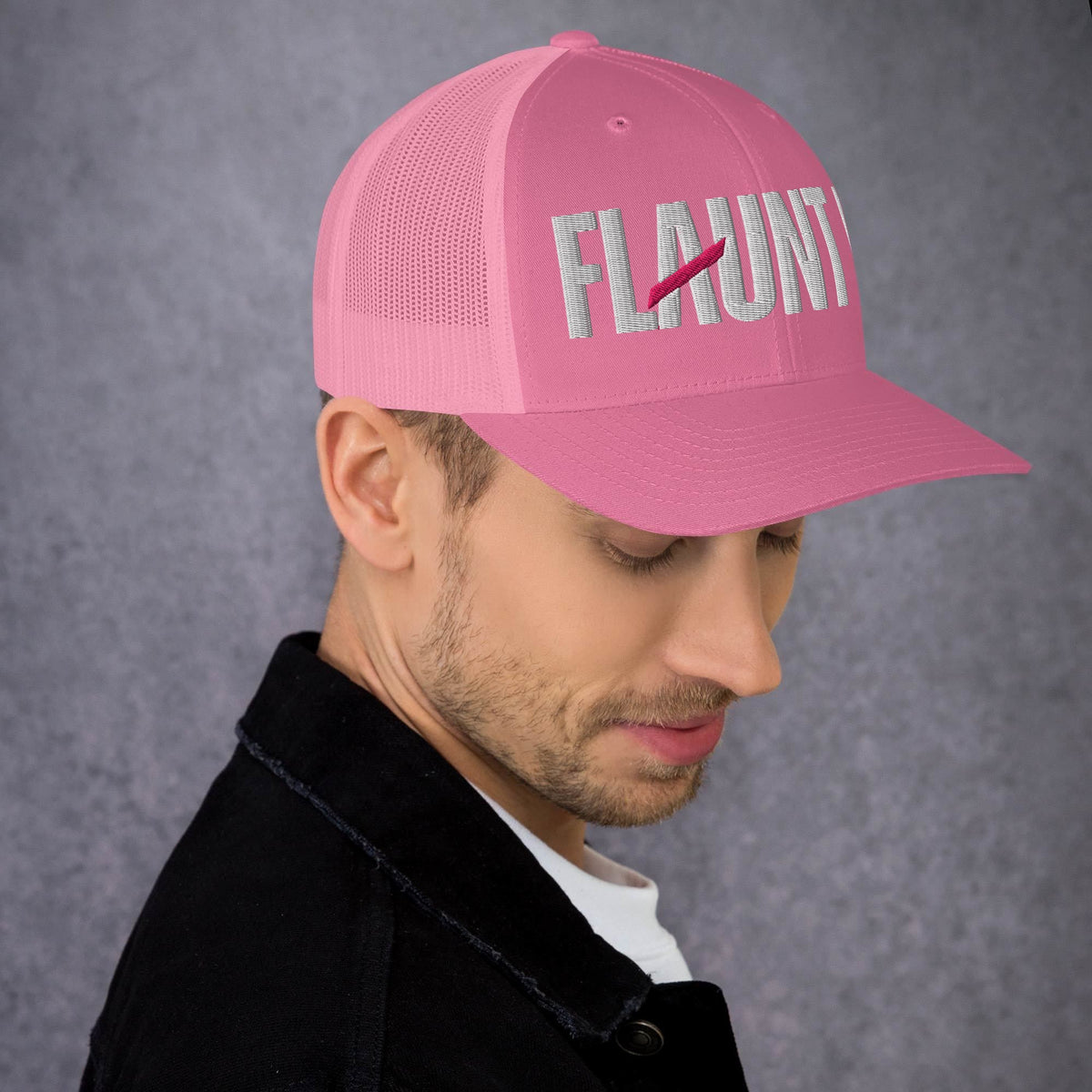 A man wearing a pink Flaunt It mesh-back trucker hat with white embroidered logo text and a curved visor.