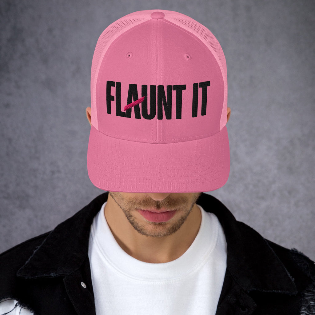 Flaunt It pink trucker hat with black embroidered wordmark, mesh back, and curved visor worn by a man.