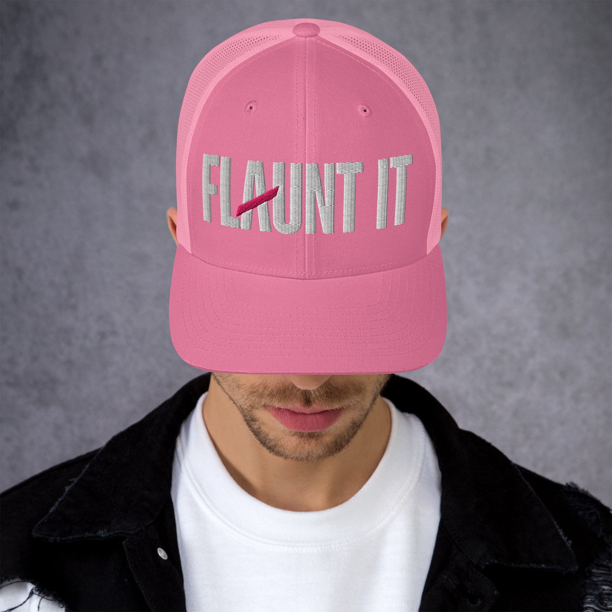 Flaunt It pink mesh-back trucker hat with white embroidered wordmark logo worn by a man in a black jacket