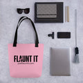 Flaunt It pink polyester canvas tote bag with black logo and handles, displayed on a grey desk with office supplies.