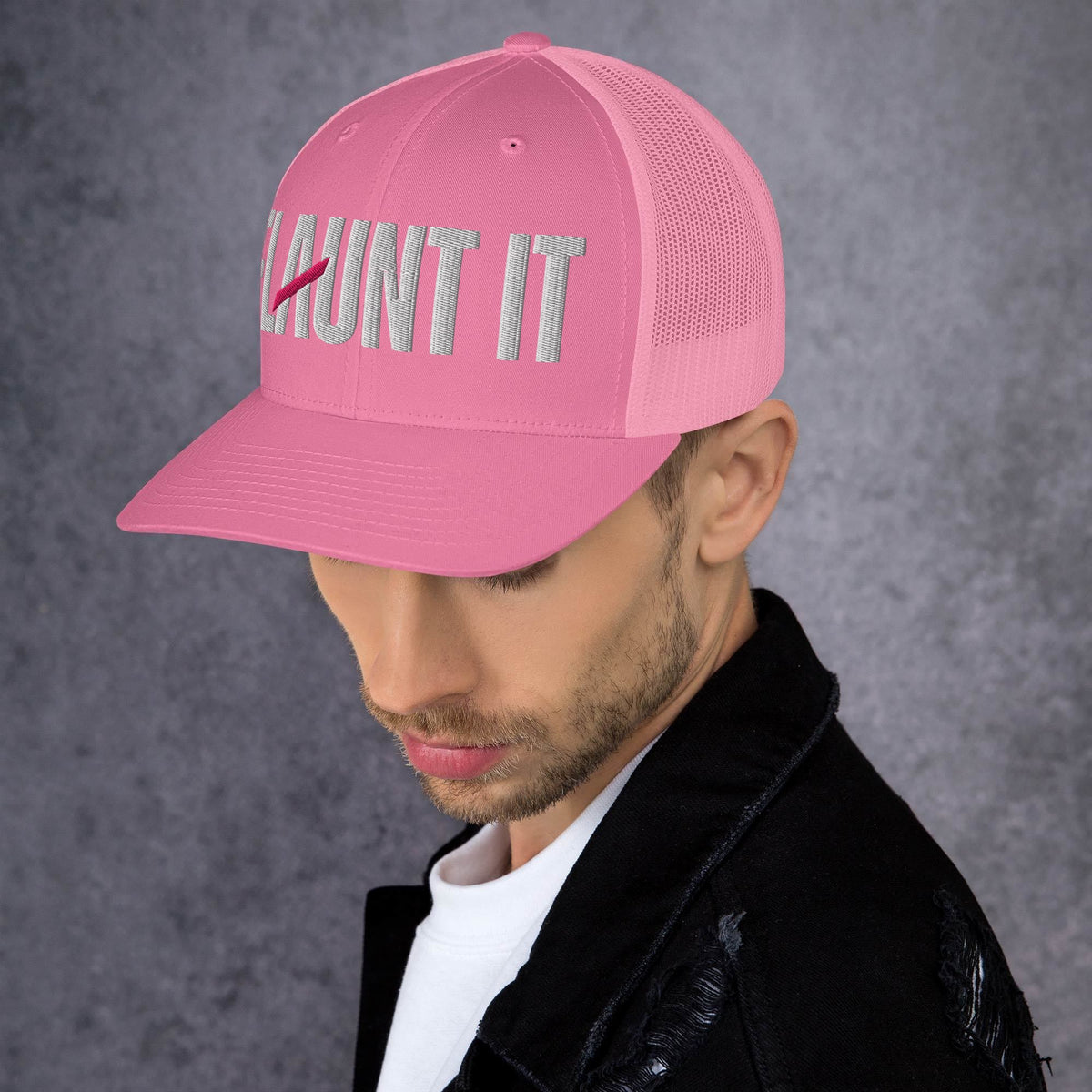 Flaunt It pink six-panel mesh back cap with white embroidered wordmark logo worn by a man against a grey background.
