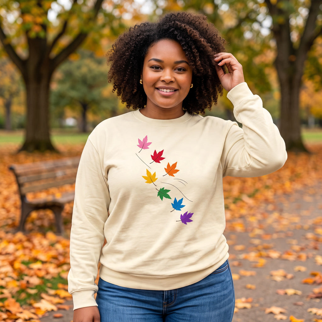 Flaunt It cream heavyweight long sleeve shirt featuring a diagonal pattern of colorful pride maple leaves in a park.