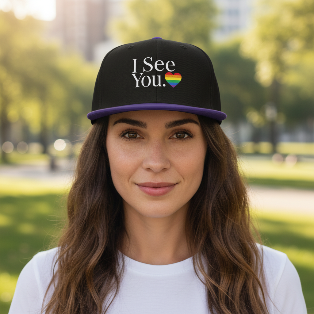 Flaunt It I See You Pride snapback cap with rainbow heart graphic on a woman in a park setting