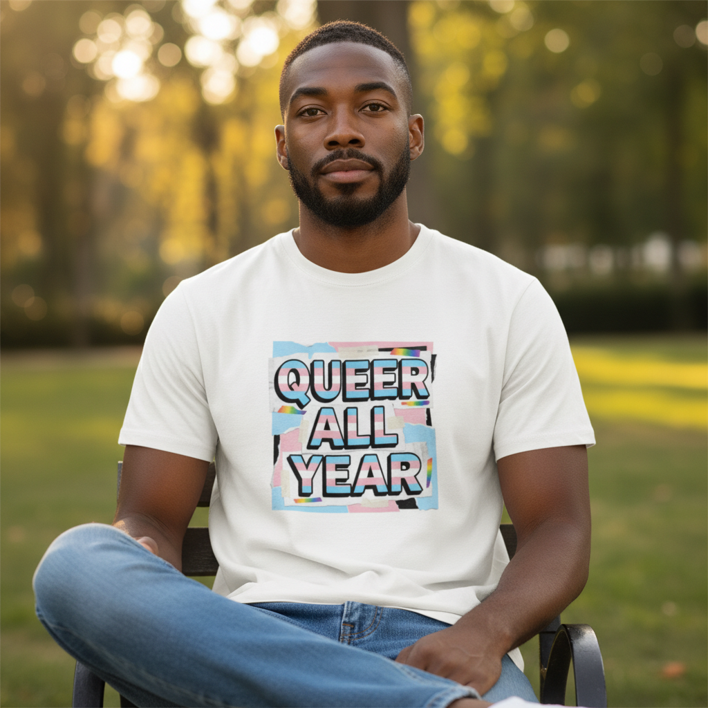 A man wearing a Flaunt It white cotton crew neck t-shirt with a Queer All Year trans pride graphic in a park setting.