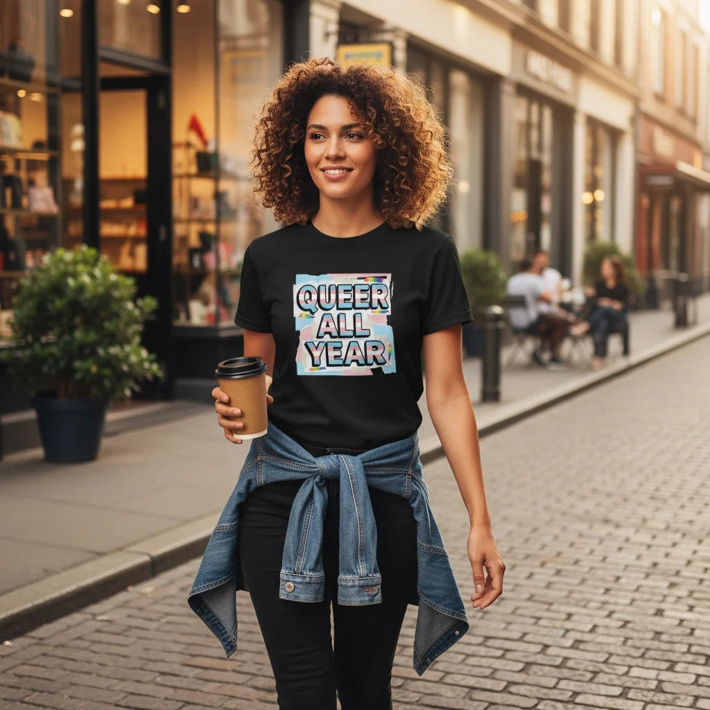 Flaunt It black unisex crew neck tee with Queer All Year trans-stripe graphic worn by a woman on a city street.