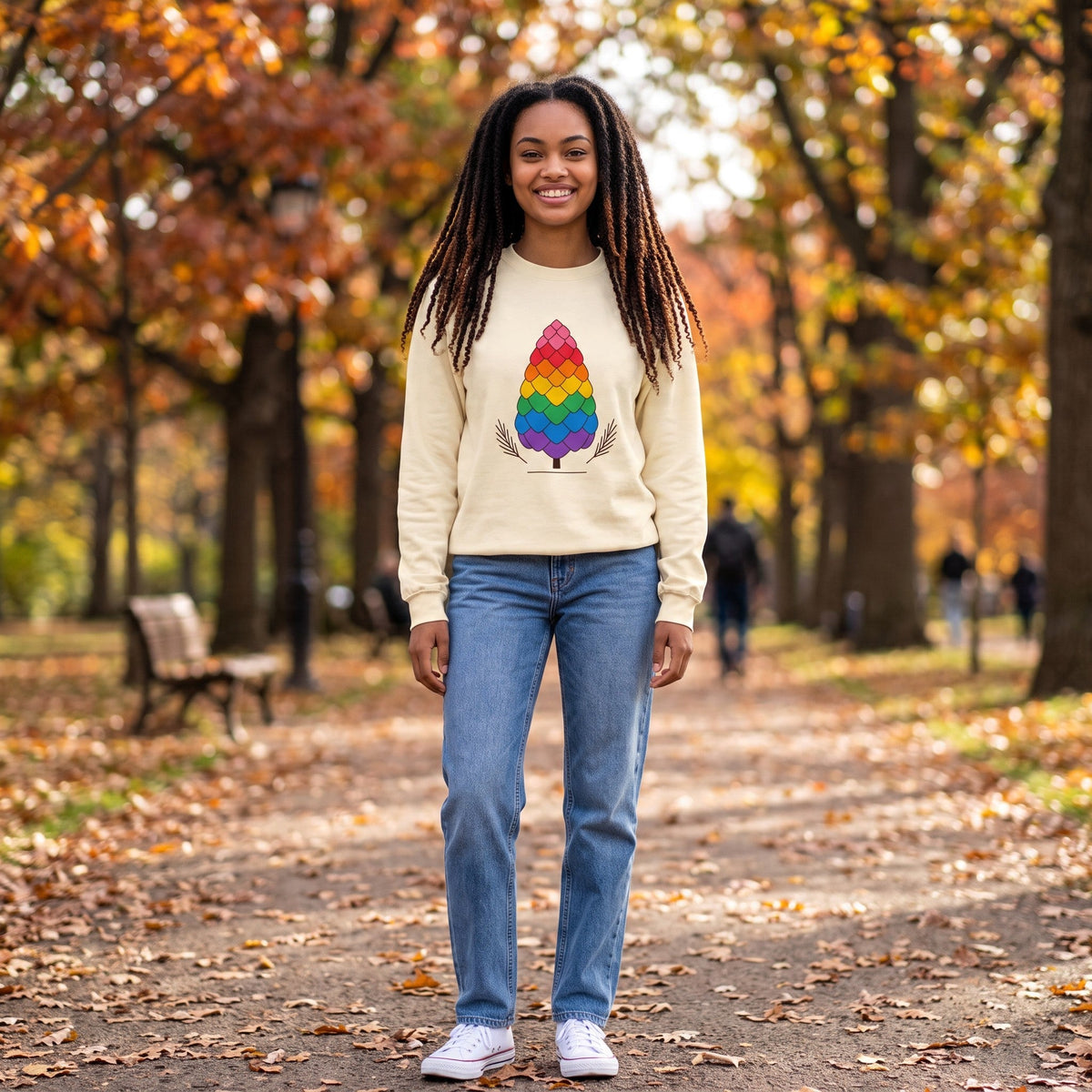 Flaunt It heavyweight long sleeve shirt with a rainbow pinecone graphic, worn by a woman in an autumn park.