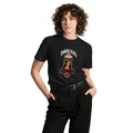 Front view of a model wearing a black Santa Vista premium unisex T-shirt with a devotional prayer-candle illustration of a female saint, cream SANTA VISTA headline, pink typing bubble, red roses and a sacred heart.