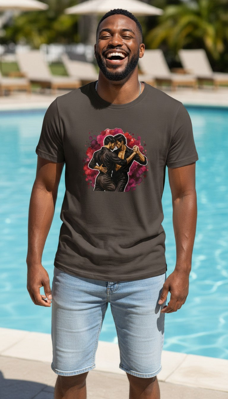 A smiling man in a coal Una Cancion Mas premium unisex T-shirt with a watercolor illustration of two women slow dancing against a magenta splash, laughing by a sunny poolside.