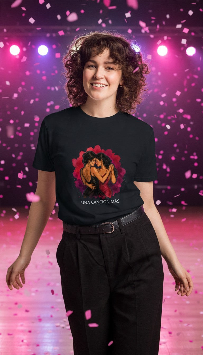 Woman wearing the Una Canción Más Premium Unisex T-Shirt in Navy dancing on a dance floor with pink confetti, with the UNA CANCIÓN MÁS watercolor two women dancing design
